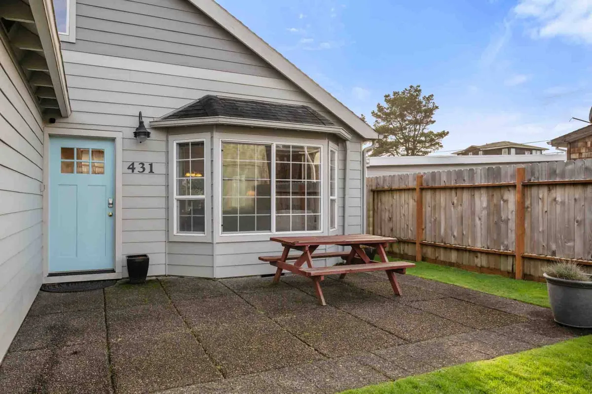 A close-up of a light blue front door and a picnic table on the patio, framed by large windows. The arrangement suggests an inviting space for relaxing, enjoying meals outdoors, and gathering with friends and family.