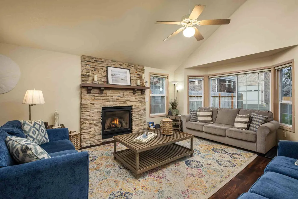 A welcoming living room featuring a gas fireplace as the focal point, surrounded by comfortable sofa seating and a decorative rug. The space is arranged for both relaxation and group gatherings, perfect for cozy family evenings or game nights. Soft lighting and thoughtful decor create a serene and inviting mood.