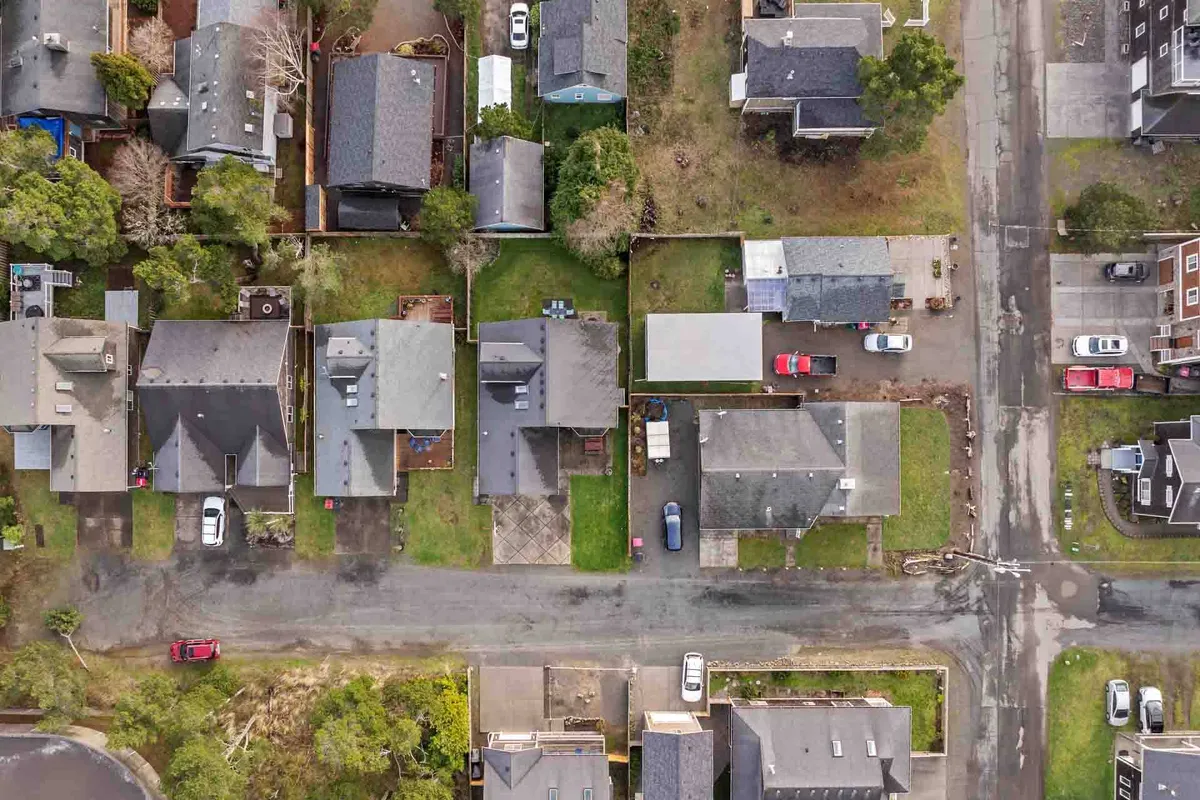 A tranquil neighborhood view featuring residential homes, tree-lined streets, driveways, and hints of community life. The inviting streetscape suggests the easy walks and neighborhood exploration near Oliver Beach House.