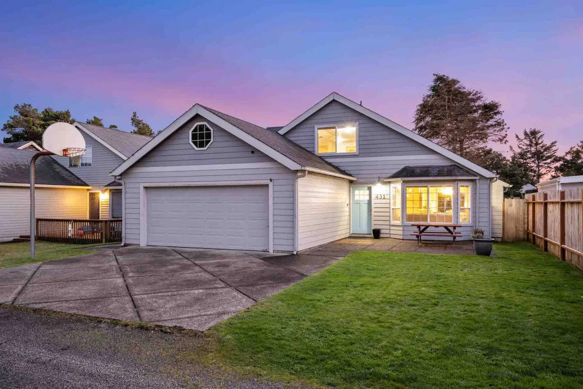 The front porch is shown with a sturdy picnic table set for outdoor dining and conversation, alongside a visible basketball hoop and garage door. The scene feels welcoming, hinting at community, family meals, and fun outdoor activities.